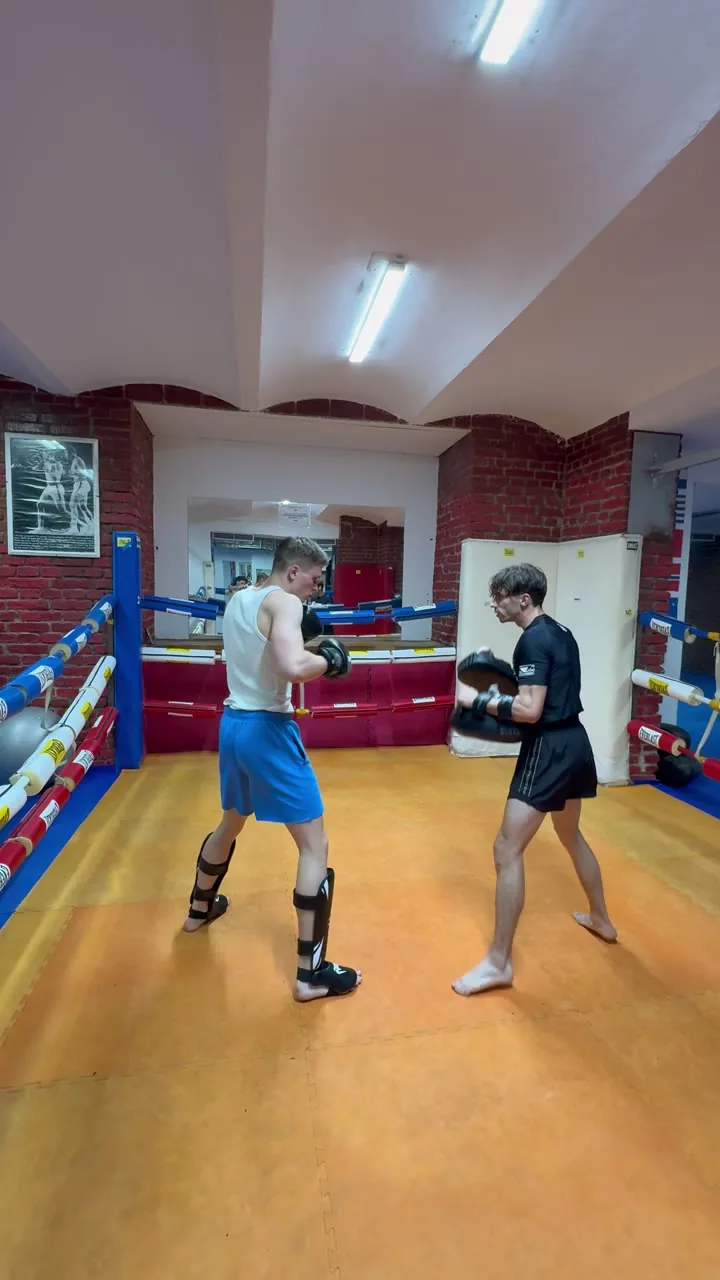 Max coaching a student on the pads in a boxing ring